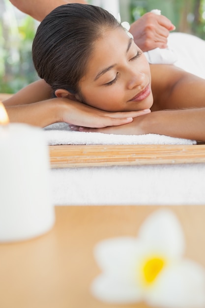 Beautiful brunette enjoying a herbal compress massage