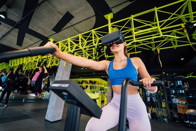 Beautiful brunette on an exercise bike in virtual reality glasses