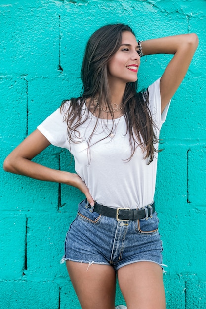 Beautiful brunette female standing by turquoise wall