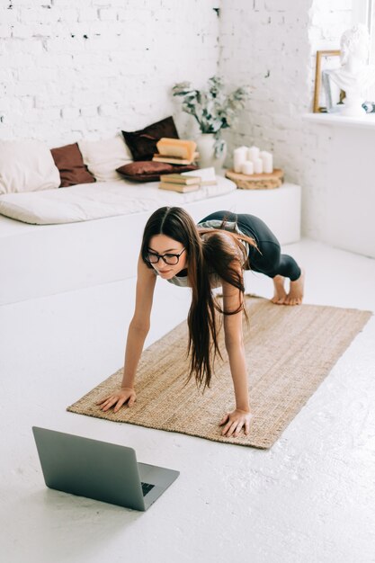 La bella donna castana di forma fisica fa gli esercizi di stretching