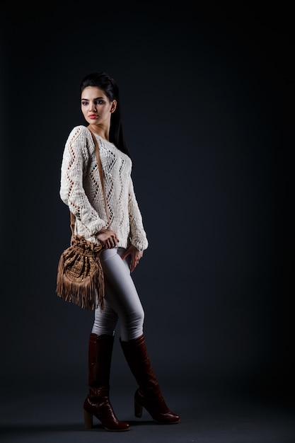 Bella ragazza castana in maglione beige e borsa marrone