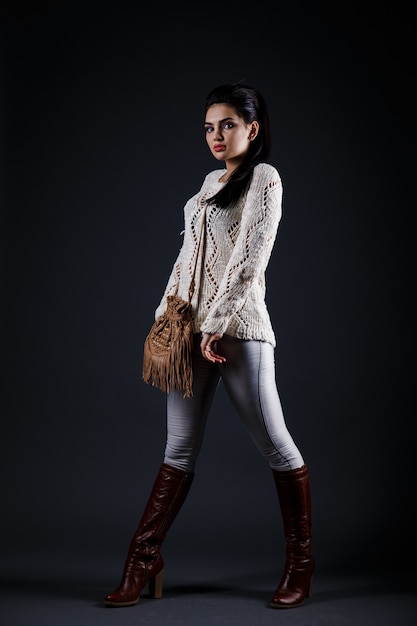 Bella ragazza castana in maglione beige e borsa marrone