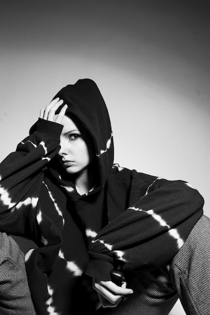 beautiful brunette girl in a black hoodie light background High quality photo