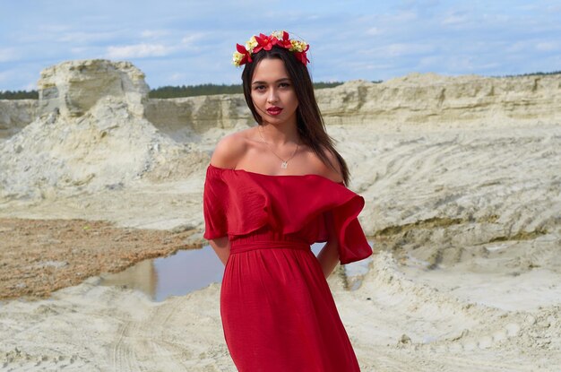 Beautiful brunette girl in a bright red dress in the desert