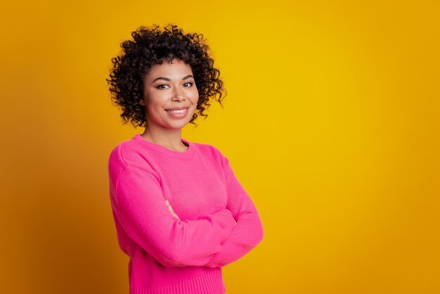 Beautiful brunette girl crossed hands beaming smile look camera isolated over yellow background