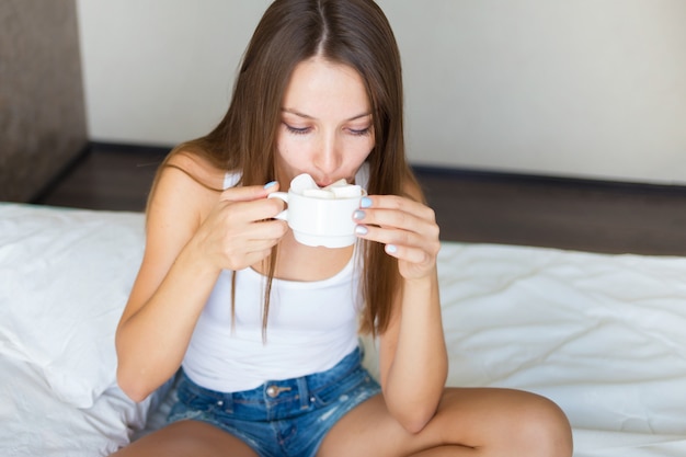 朝食を食べて、コーヒーを飲みながら美しいブルネットの少女