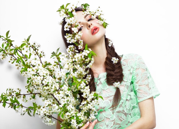 Beautiful brunette girl in green summer dress with a gentle romantic makeup pink lips holding flowers The beauty of the face