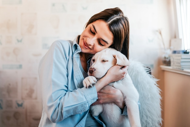 Beautiful brunette girl hugging her puppy at home. Close-up.