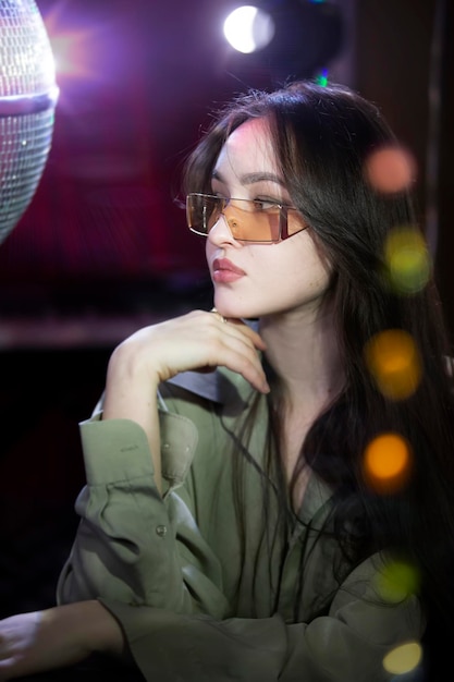 A beautiful brunette girl is sitting in a bar on a bokeh background