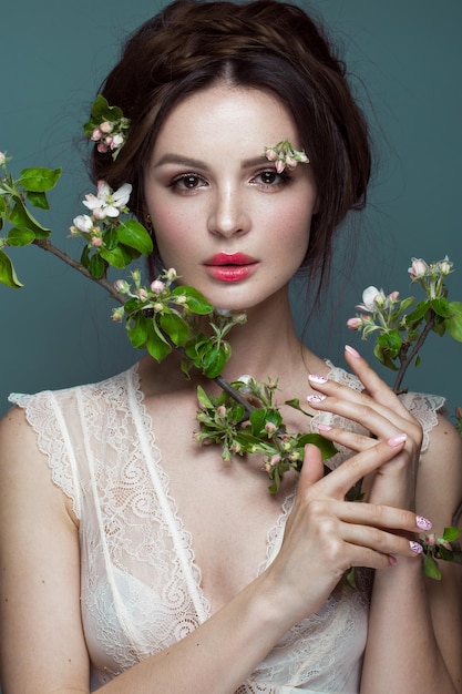 Beautiful brunette girl in lingerie with a gentle romantic makeup pink lips holding flowers The beauty of the face