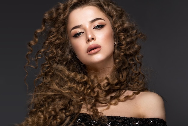 Beautiful brunette girl in move with a perfectly curly hair and classic makeup Beauty face
