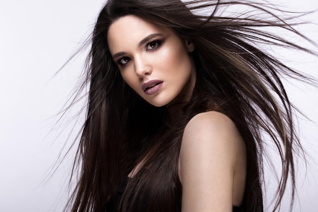 Beautiful brunette girl in move with a perfectly smooth hair and classic makeup Beauty face