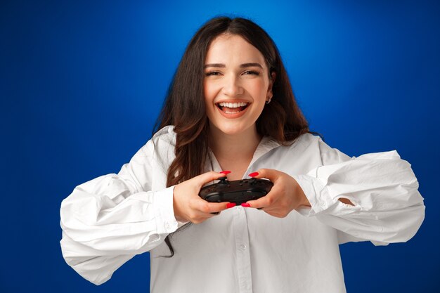 Beautiful brunette girl playing video games against blue background