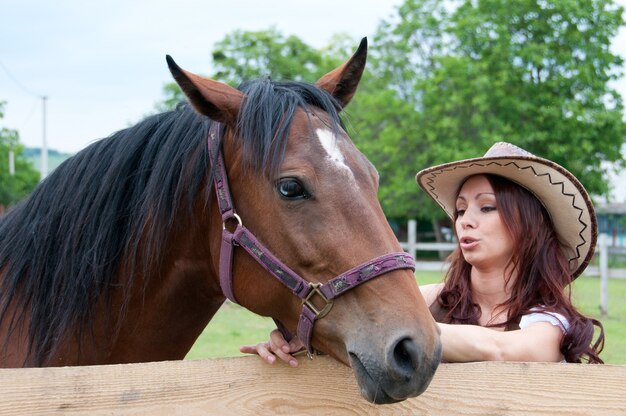 Beautiful brunette girl speaks with a horse