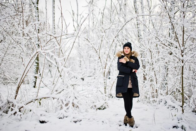 Beautiful brunette girl in winter warm clothing Model on winter jacket and black hat