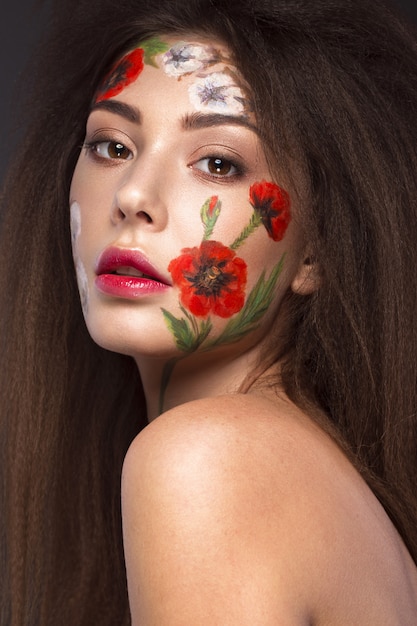 Beautiful brunette girl with curls and a floral pattern on the face. Beauty flowers.