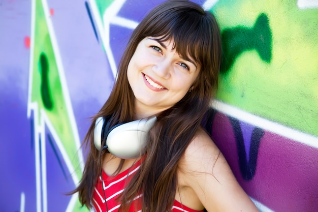 Photo beautiful brunette girl with headphones and graffiti wall
