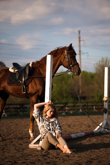 Beautiful brunette girl with her horse outdoors.