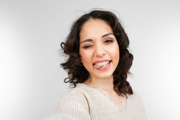 Beautiful brunette girl with makeup takes selfie while grimacing