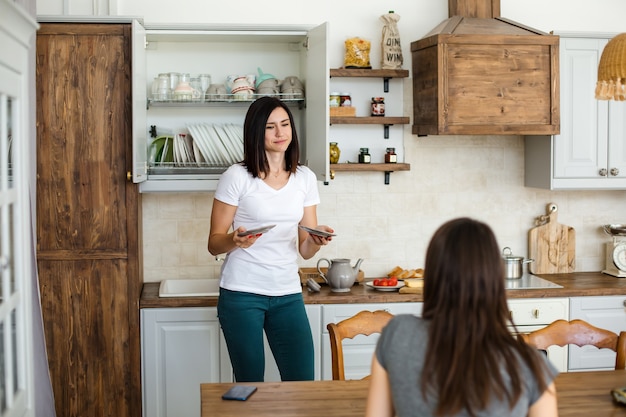 Beautiful brunette girls chatting in the house in the kitchen. 