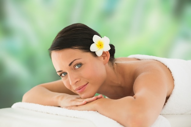 Beautiful brunette relaxing on massage table smiling at camera