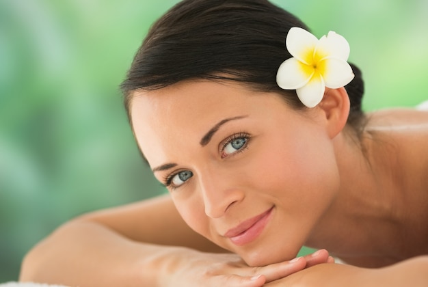 Beautiful brunette relaxing on massage table smiling at camera