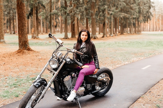 The beautiful brunette riding a motorcycle in the park