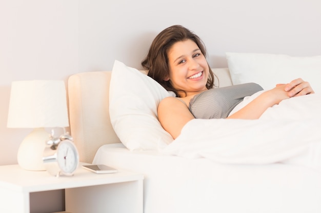 Beautiful brunette smiling in her bed