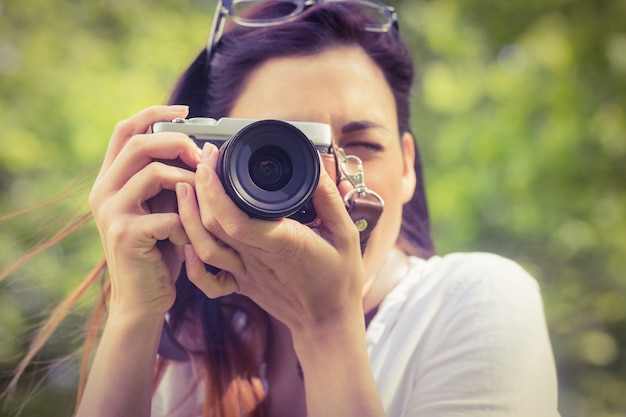 Beautiful brunette taking photo in the park