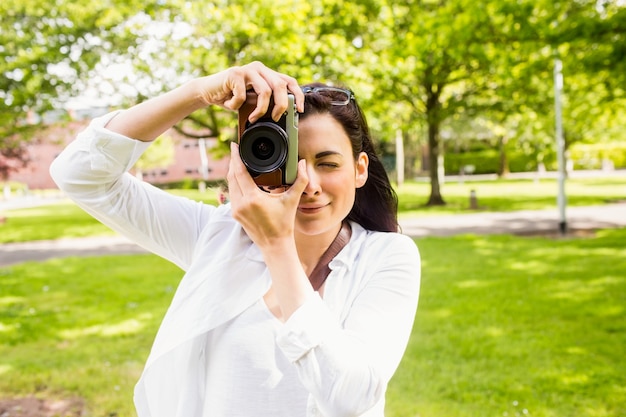 Beautiful brunette taking photo in the park