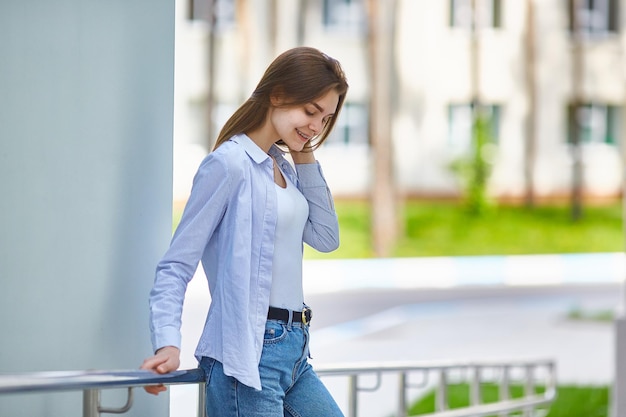 彼女の歯に中かっこを持つ美しいブルネットの十代の少女街の晴れた夏の日に通りを歩いて笑顔