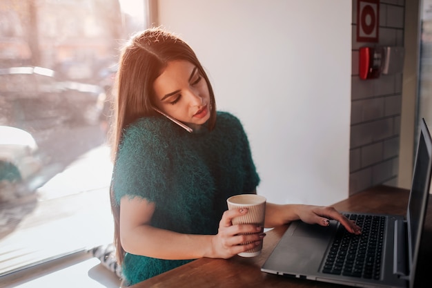 Photo beautiful brunette using laptop in cafe