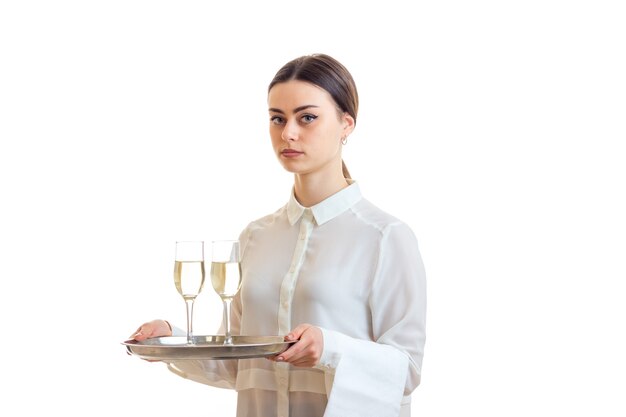 Beautiful brunette waitress in uniform holding a trey with wine isolated on white background