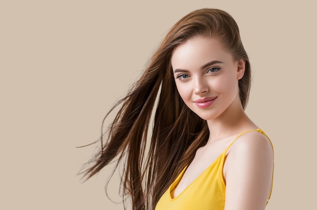 Beautiful brunette with long smooth hair in yellow dress natural portrait. Color background. Brown