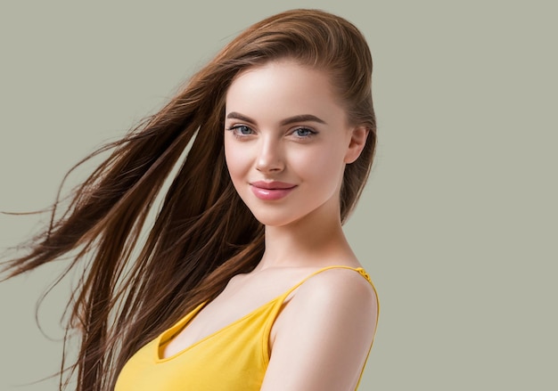 Beautiful brunette with long smooth hair in yellow dress natural portrait. Color background. Green