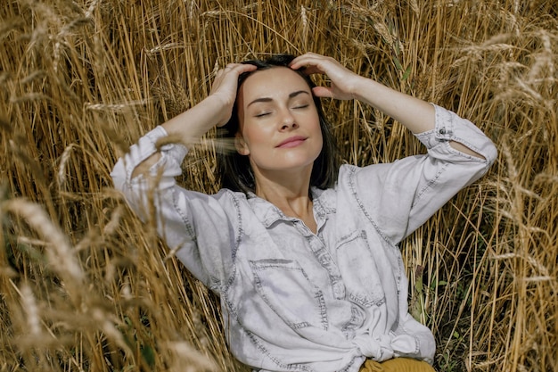 写真 ウクライナの畑の小麦の小穂に横たわる短い髪の美しいブルネットの女の子