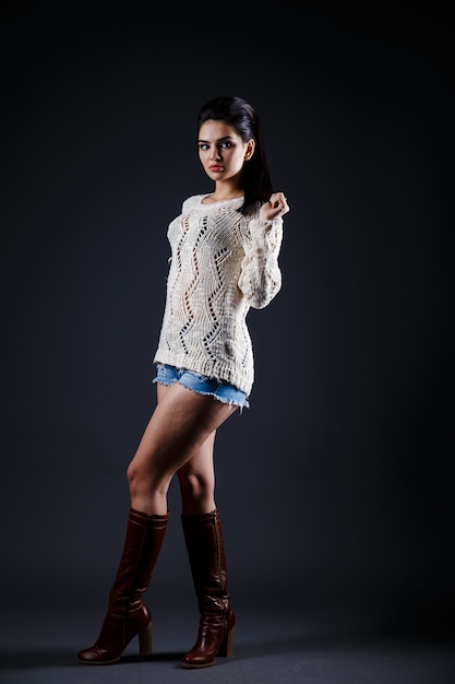 Beautiful brunette woman in beige sweater and blue shorts