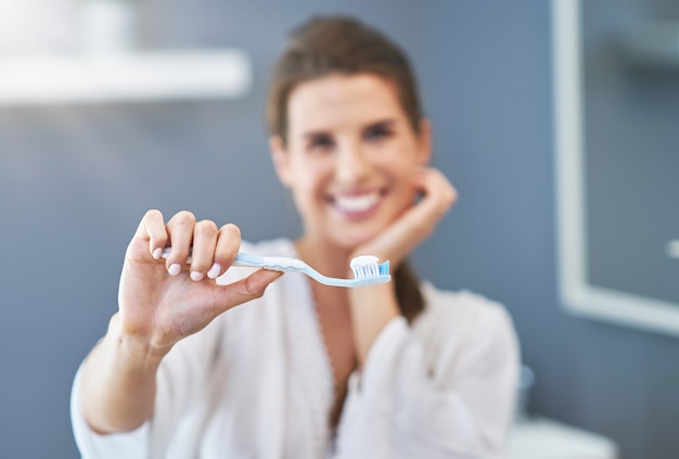 Beautiful brunette woman brushing teeth in the bathroom