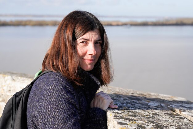 Beautiful brunette woman in casual winter jacket on beach autumn coast