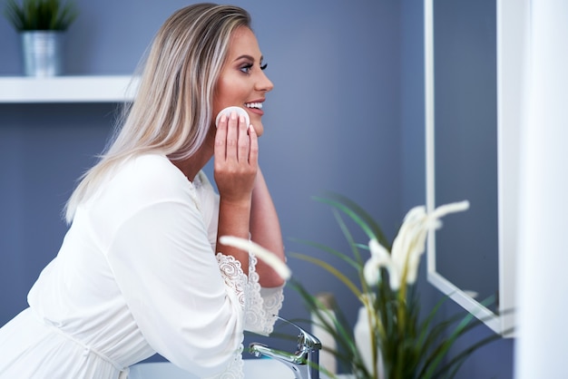 Beautiful brunette woman cleaning face in the bathroom