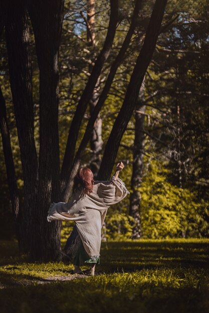 Beautiful brunette woman dancing in the morning forest in summer