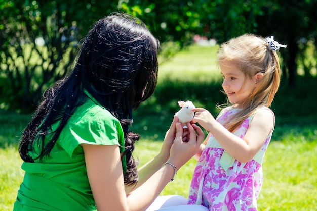 Beautiful brunette woman embrace children daughter in summer park.