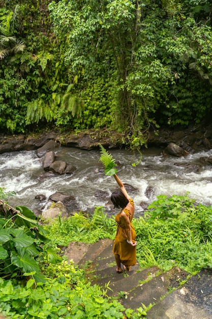 Красивая брюнетка женщина, держащая листья, идя шаг за шагом к горной воде, stock photo