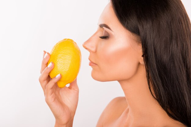 Beautiful brunette woman holding a lemon