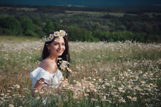 Beautiful brunette woman is enjoying spring in a field of daisies