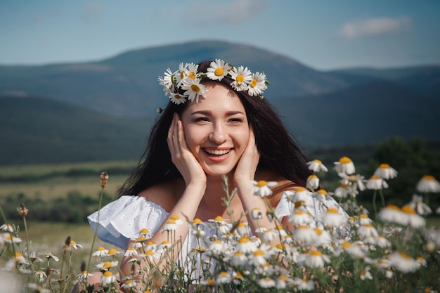 Beautiful brunette woman is enjoying spring in a field of daisies