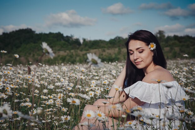 Beautiful brunette woman is enjoying spring in a field of daisies