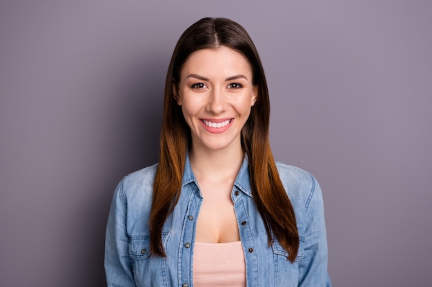 beautiful brunette woman in jeans shirt posing against the purple wall