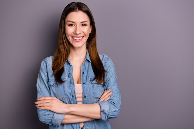 beautiful brunette woman in jeans shirt posing against the purple wall