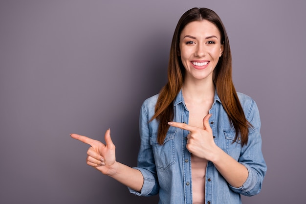 beautiful brunette woman in jeans shirt posing against the purple wall